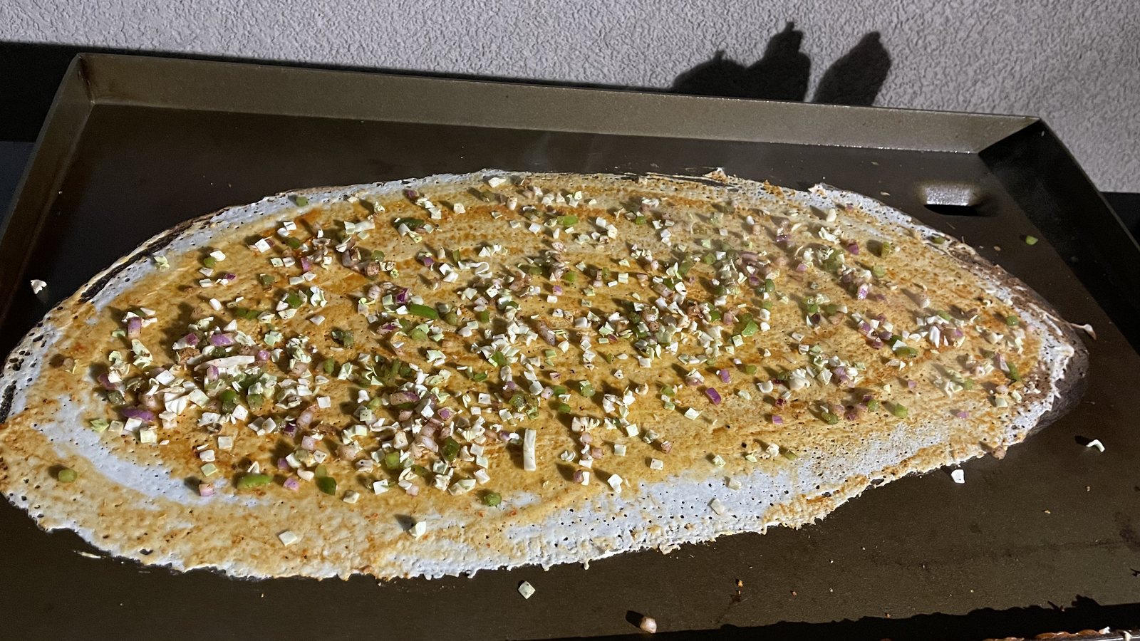 A fresh dosa cooking on the griddle at a Honest live dosa station