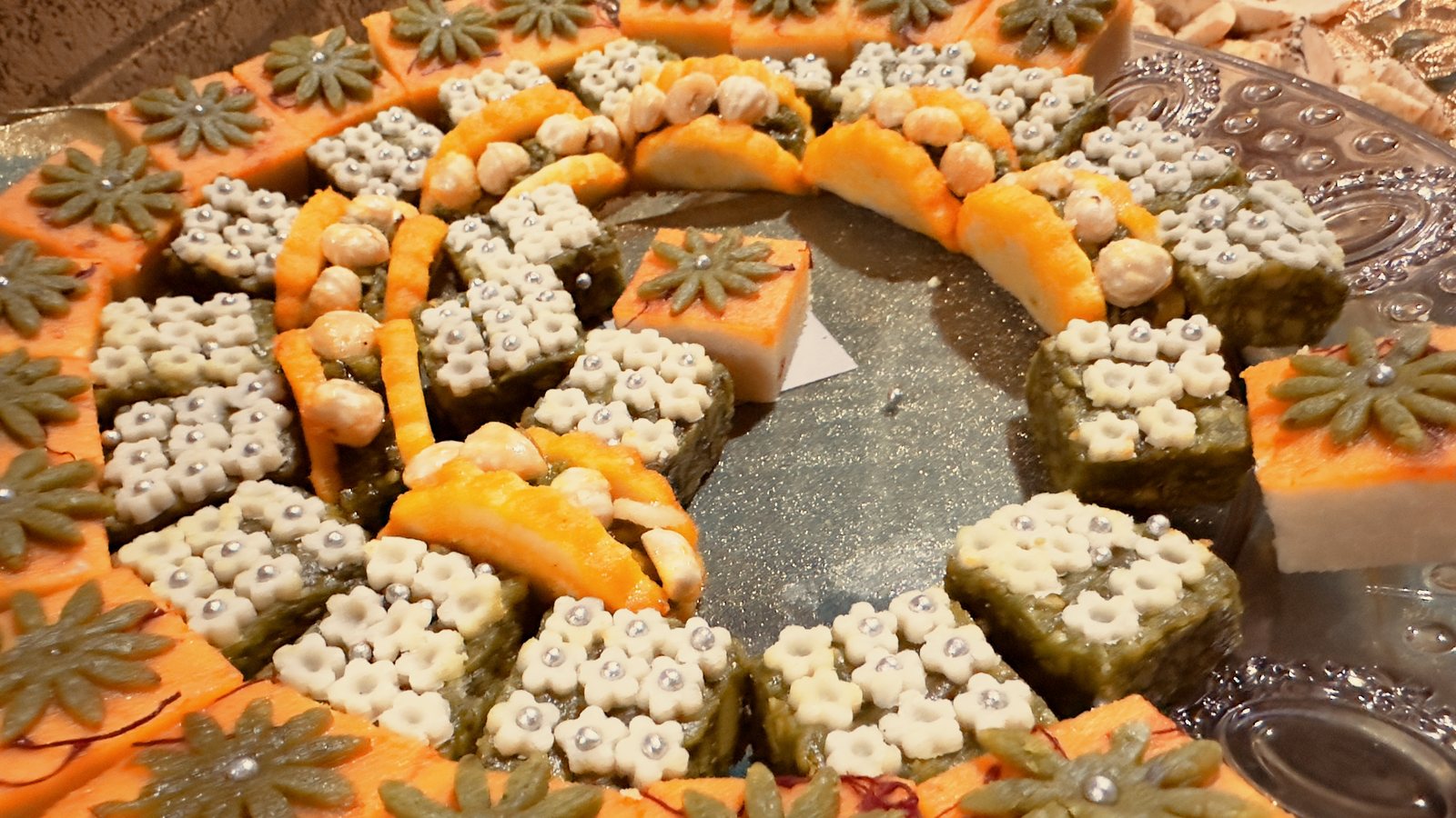 Assorted Indian mithai arranged on a mirror platter at a Honest event