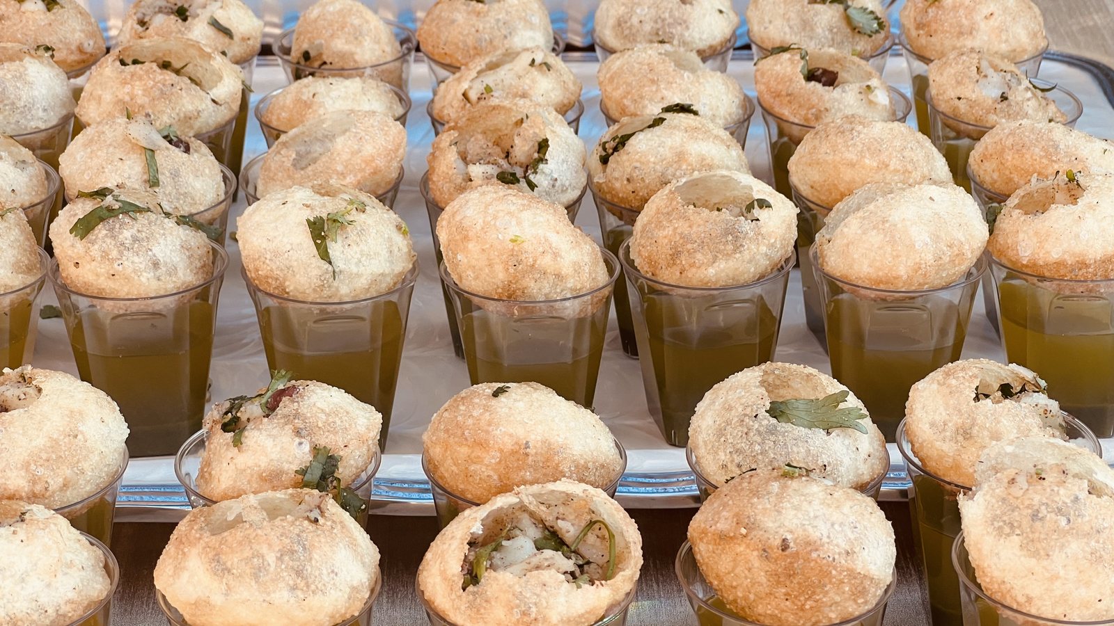 Fresh pani puri shooters lined up at a Honest catering counter